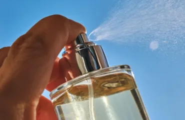 Svizhi uniseks aromaty dlya ofisu y lita minimalizm u flakoni Close-up of a hand pressing a perfume spray bottle outdoors, mist spraying into a clear blue sky.
